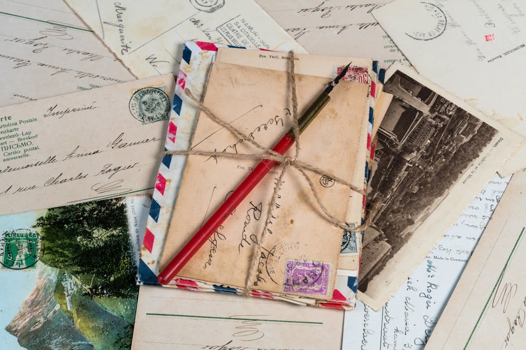 Coming to Camp! A collection of vintage postcards and envelopes tied with twine, featuring a pen and old stamps.