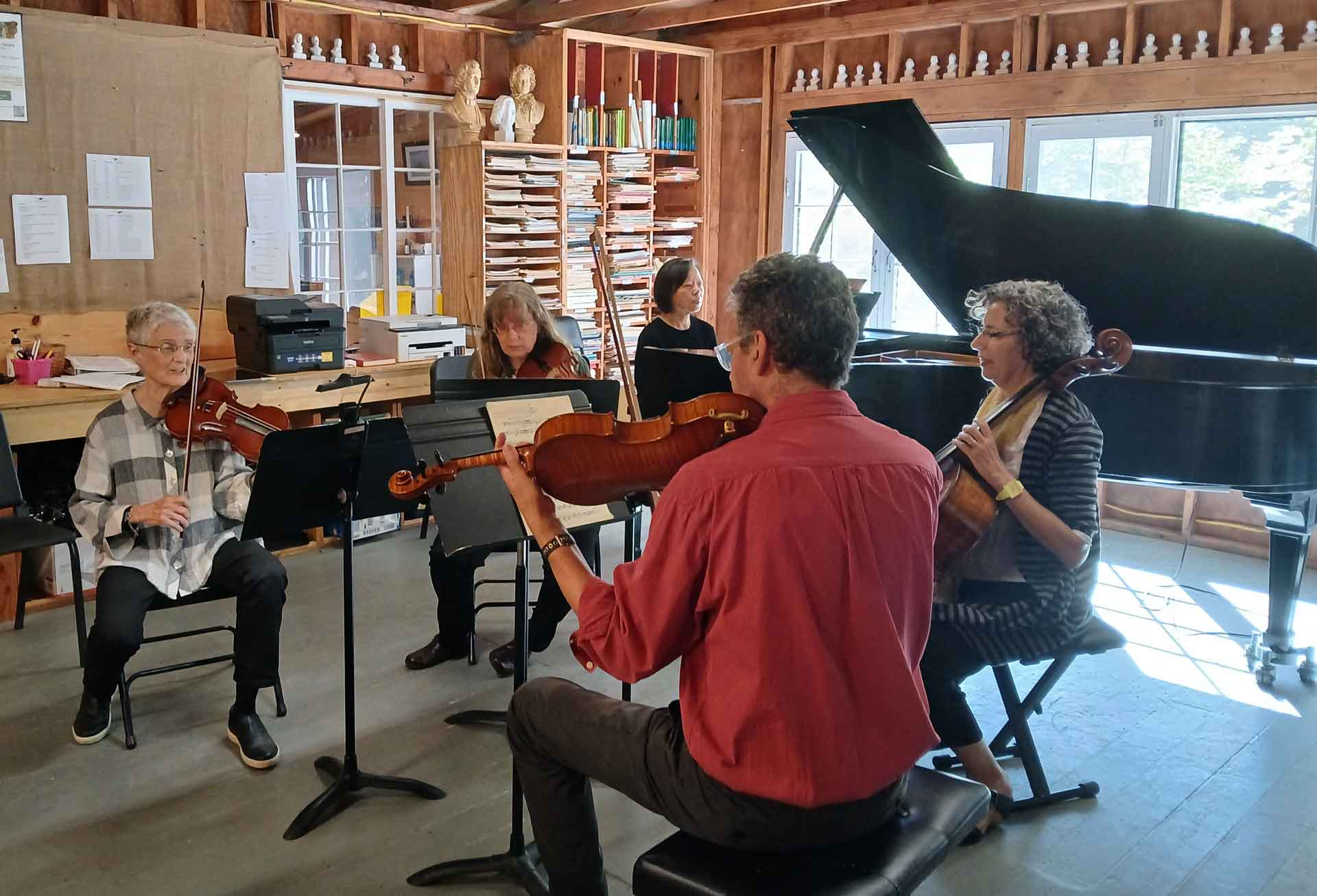 Point CounterPoint Five musicians rehearse together in a sunlit room, exploring Point CounterPoint with string instruments and a grand piano, surrounded by shelves and scattered papers.